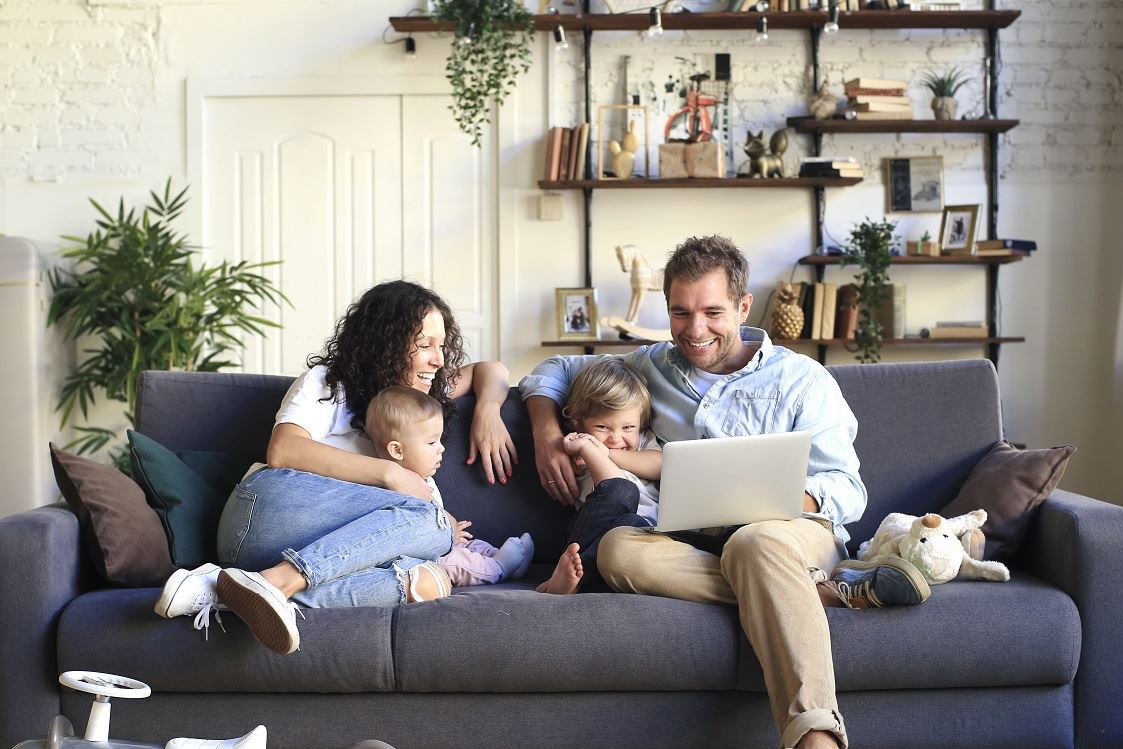 Family sitting on couch laughing and looking at a laptop